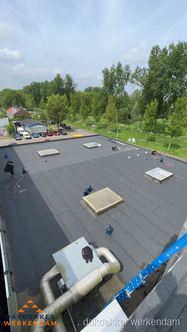 Dakdekker aan het werk op groot plat dak met bitumen in Werkendam Dakdekker aan het werk op groot plat dak met bitumen in Werkendam