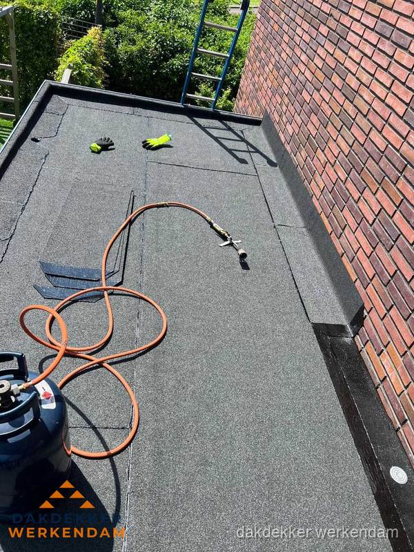 Plat dak met bitumen en brandgereedschap van dakdekkersbedrijf in Werkendam