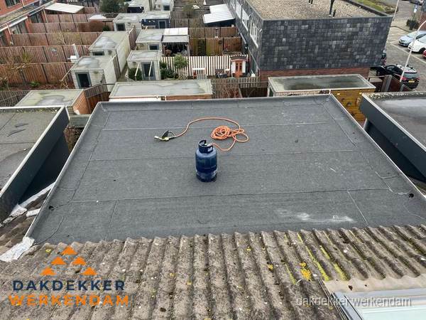 Plat dak met nieuwe bitumen dakbedekking en brandgereedschap in Werkendam