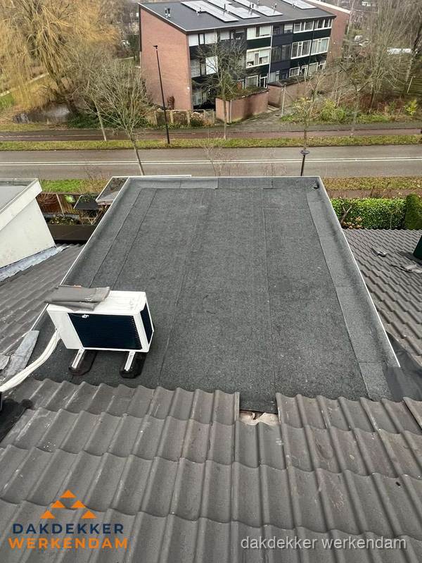 Plat dak inspectie met bitumen bedekking naast schuin pannendak in Werkendam