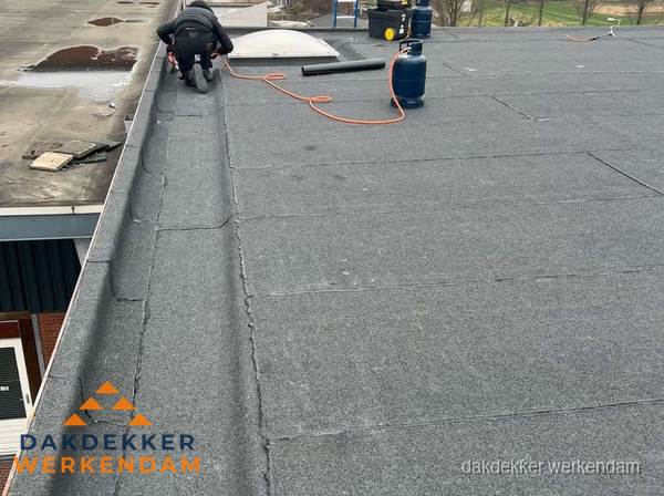 Dakdekker repareert bitumen dakbedekking op groot plat dak in Werkendam